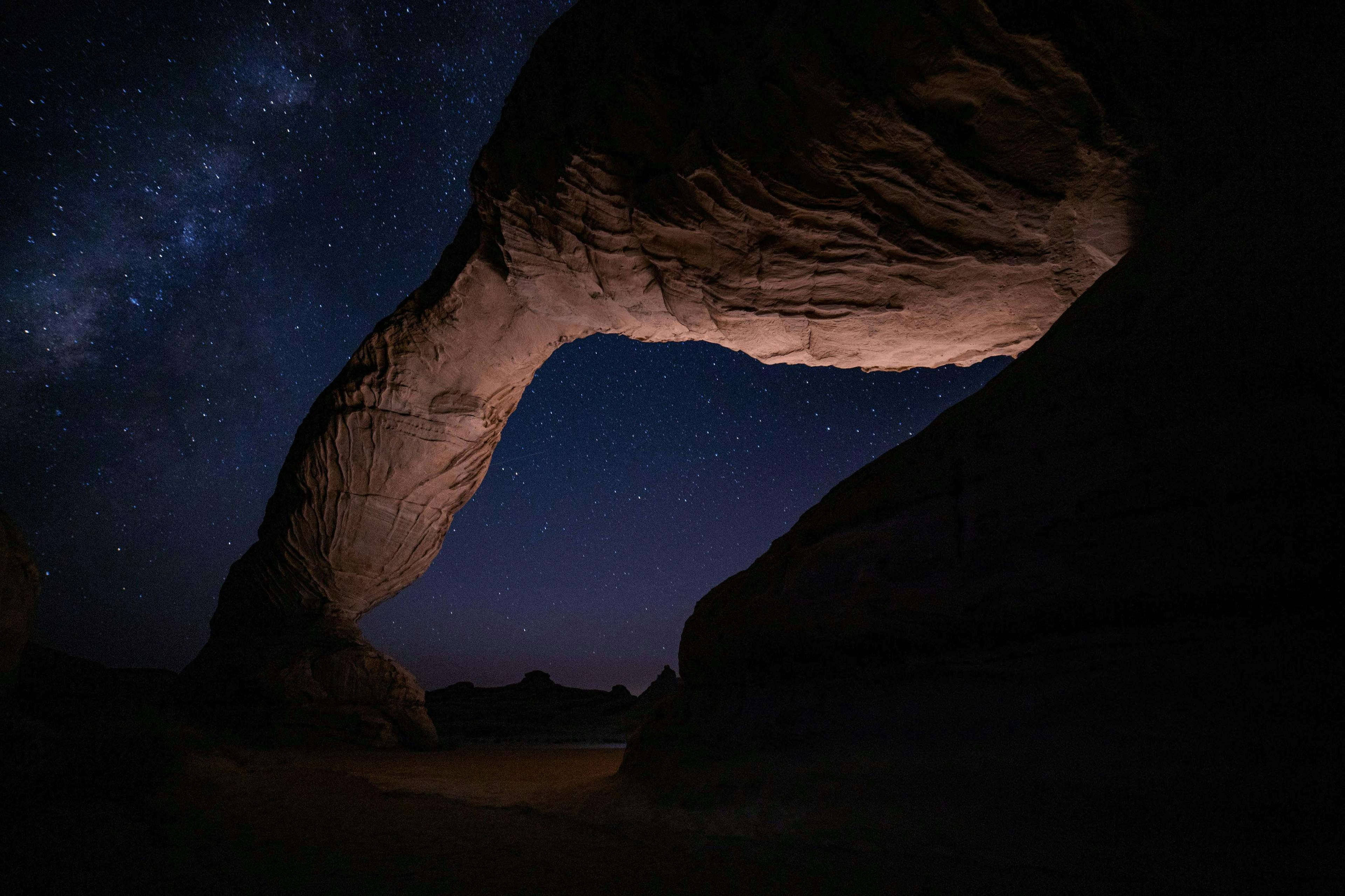 A starry night behind a rock formation.